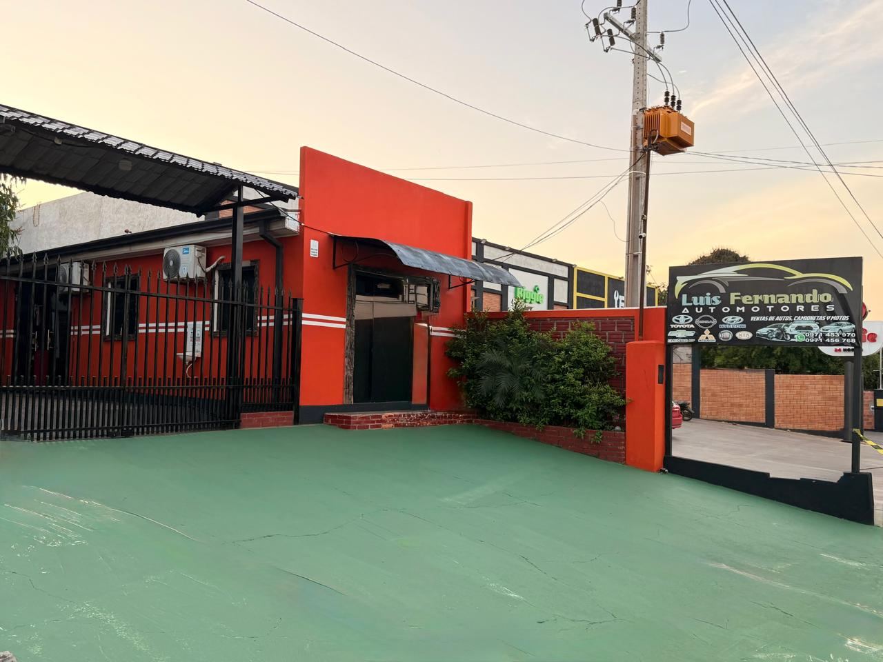 Fachada naranja del local de Luis Fernando Automotores al atardecer